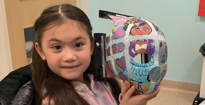 Jasmine holding her hand painted radiotherapy mask